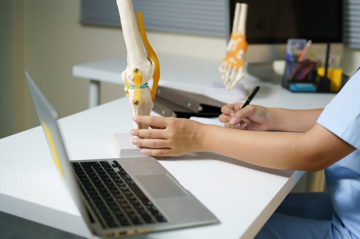 Modelo anatómico de cadera junto a una laptop, representando la planificación quirúrgica asistida por tecnología