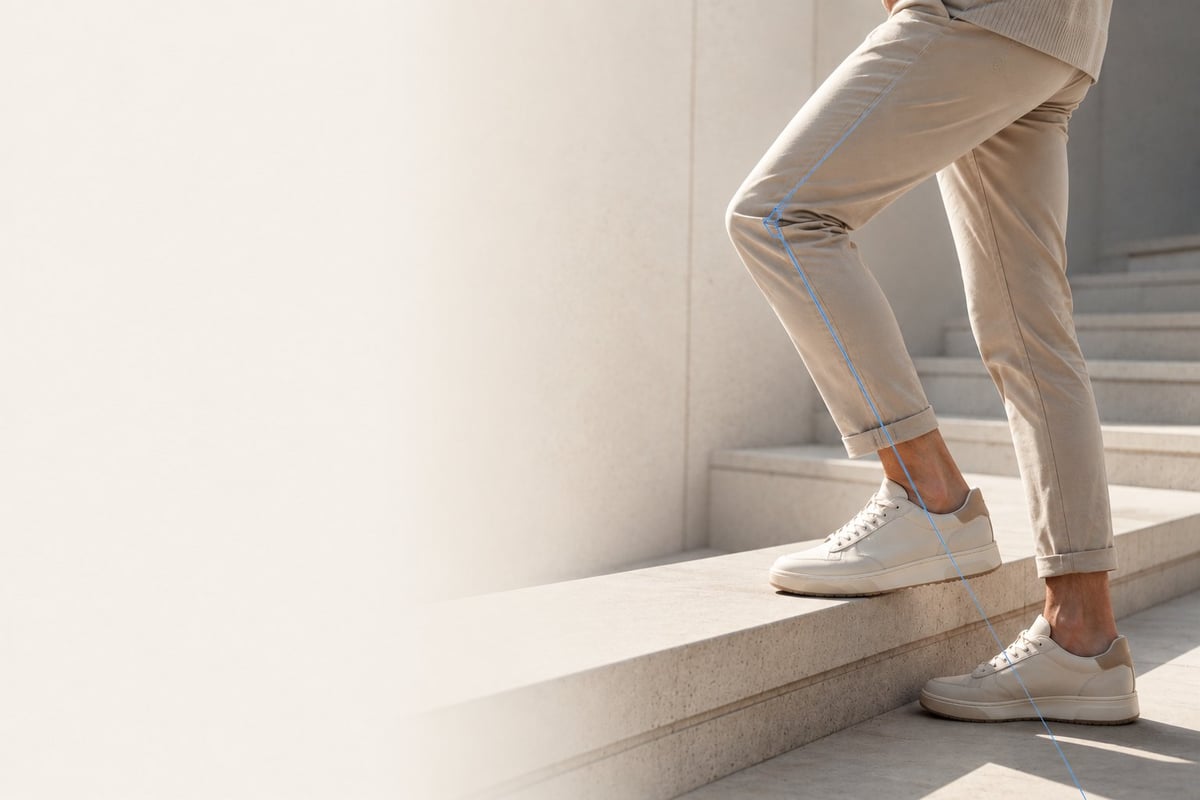 Person wearing beige pants and white sneakers standing on a concrete step in bright sunlight