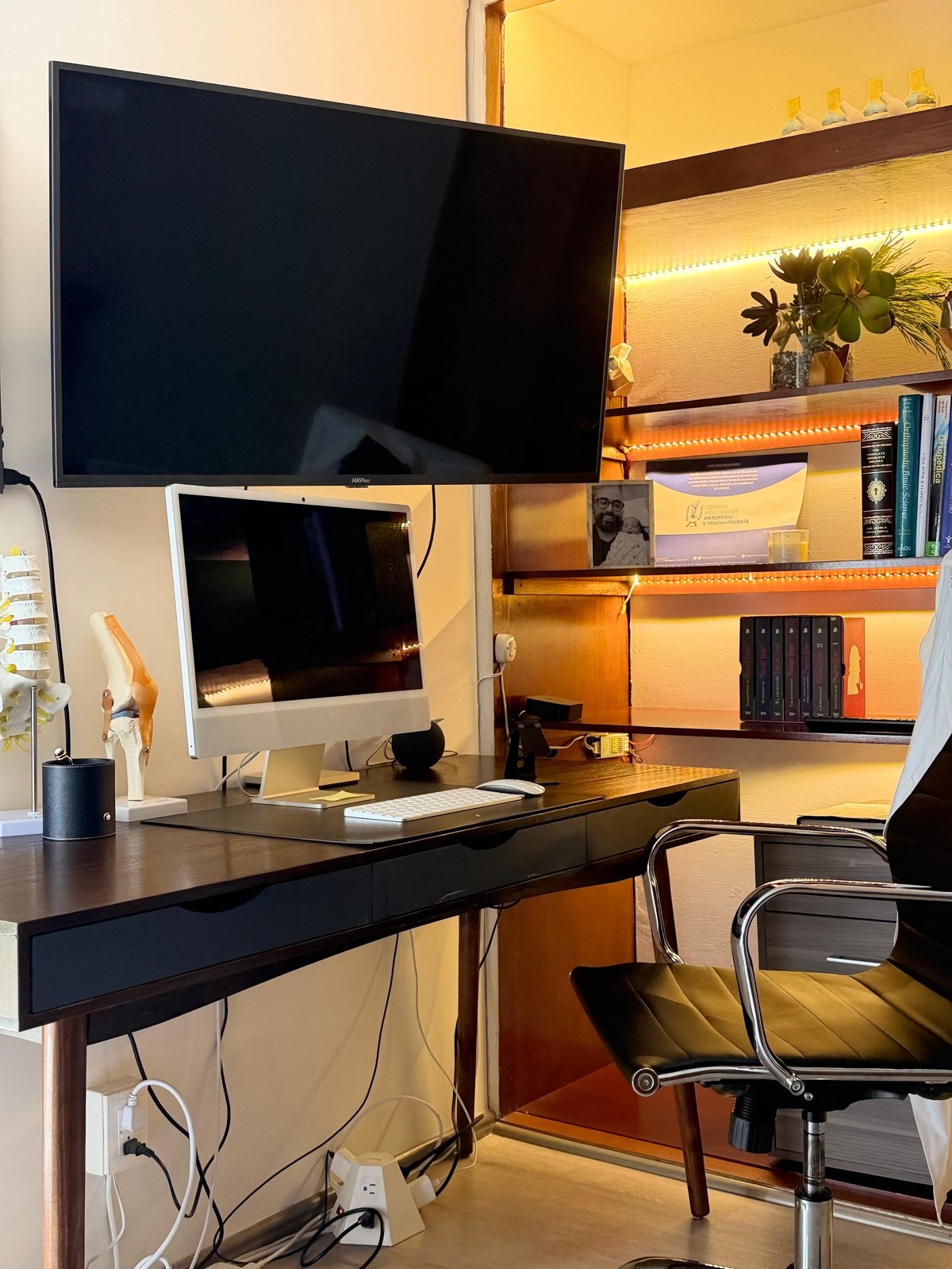 Escritorio con monitor y estantería iluminada en el consultorio